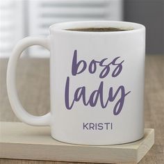 a white coffee mug with the words boss lady on it sitting on a wooden coaster