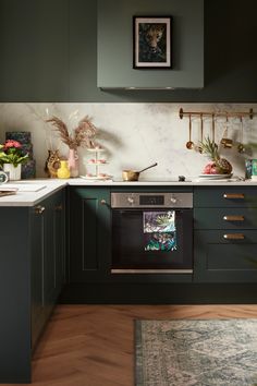 a kitchen with dark green cabinets and white counter tops, an oven in the center