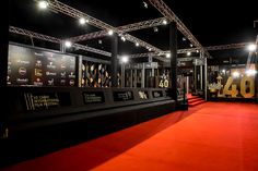 a red carpeted area with black and gold trophies on it's sides at night