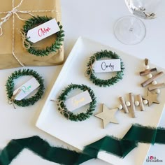 some christmas decorations are on a plate near a wine glass and wrapped gift bags with name tags