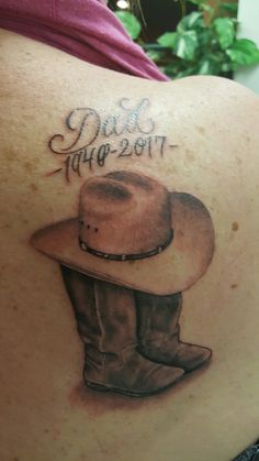 the back of a woman's shoulder with a cowboy hat and date tattoo on it