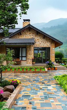 a stone house with plants and flowers in the front yard