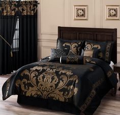 a bed with black and gold comforters in a bedroom next to a window covered by curtains