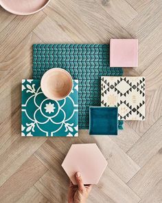 a person's hand on top of a rug next to various tiles and other items