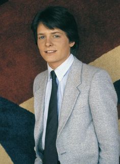 a young man in a suit and tie posing for a photo with his hands in his pockets