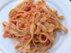 a white plate topped with pasta covered in sauce