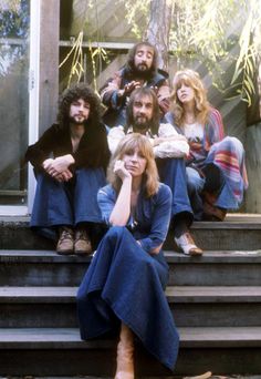 a group of people sitting on the steps in front of a building with their hands to their face