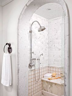 a bathroom with white tile and marble walls, along with a shower head mounted on the wall