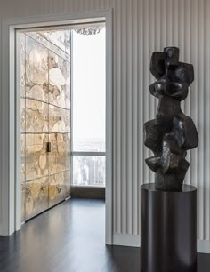 a black sculpture sitting in front of a window on top of a hard wood floor