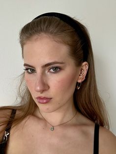 a young woman wearing a black bra top and piercings on her ears is looking at the camera