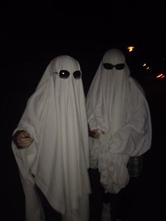 two people in white ghost costumes holding hands