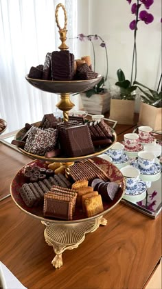 three tiered trays filled with different types of chocolate on top of a wooden table