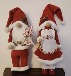 two red and white santa claus dolls standing next to each other on top of a shelf