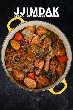 a pan filled with chicken and vegetables on top of a black counter next to a yellow spatula