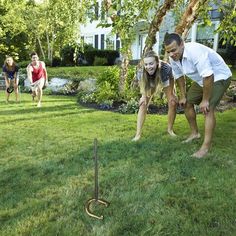 two people are playing with a snake in the yard