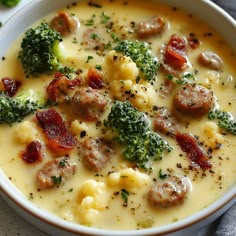 a white bowl filled with broccoli, sausage and cauliflower in cream sauce