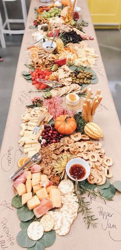 a long table covered in lots of different types of cheeses and crackers on it