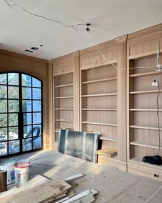 an empty room with bookshelves and tools on the floor in front of large windows