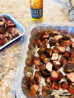 two plastic containers filled with meat sitting on top of a counter next to bottles of beer