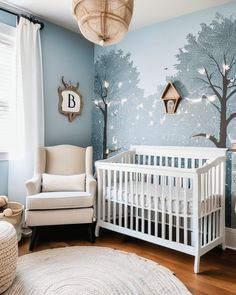 a baby's room decorated in blue and white with trees on the wall, crib, rocking chair, and lamp