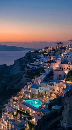 an aerial view of a town at night with the ocean in the background and lights on