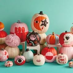 a group of pumpkins sitting on top of each other in front of a blue wall