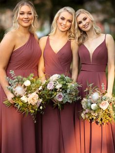 three bridesmaids in maroon dresses with flowers and greenery on their bouquets