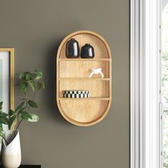 a wooden shelf with two black vases on it next to a potted plant