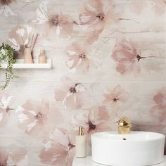 a white sink sitting next to a wall with pink flowers painted on it's side