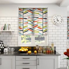 the kitchen is decorated in white and has colorful curtains on the windows sill, along with an assortment of fruit