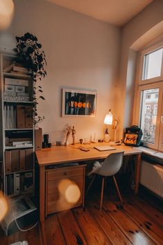 a room with a desk, chair and lamp in it next to a large window