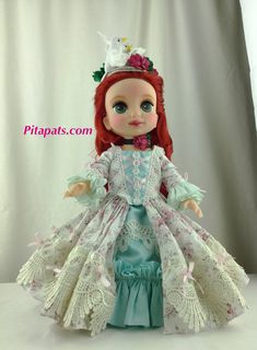 a doll with red hair wearing a blue dress and a tiara on her head