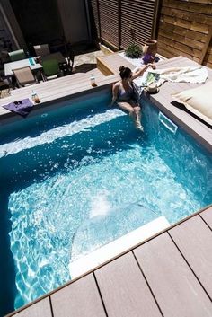 a woman sitting on the edge of a swimming pool