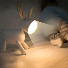 a lamp that looks like a reindeer is on a bed with white sheets and pillows