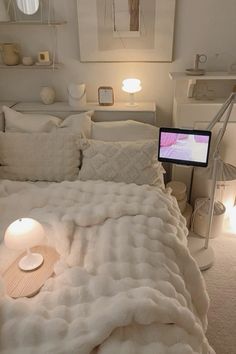 a bed with a laptop on top of it in a room filled with white furniture