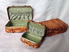 two old suitcases sitting side by side on a white sheeted surface, one opened and the other closed