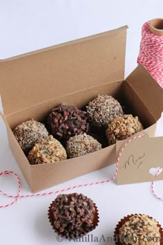 a box filled with chocolate covered donuts next to a spool of twine