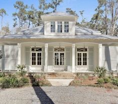 a white house surrounded by trees and bushes