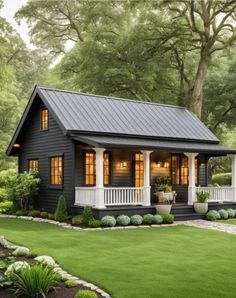 a small black house in the middle of a lush green yard with trees and bushes