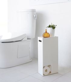 a white toilet sitting in a bathroom next to a plant