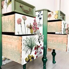 three drawers with flowers painted on them and green legs are sitting in front of a mirror