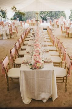 the table is set up for an event with pink flowers and white linens on it