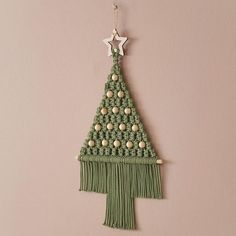 a crocheted christmas tree hanging on a wall with beads and tassels