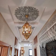 an ornate ceiling light hanging from the ceiling in a room with wooden doors and windows