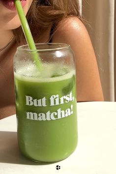 a woman drinking a green smoothie with a straw in her mouth and the words but first, matcha written on it