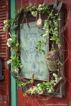 a sign hanging on the side of a building with plants growing out of it's sides