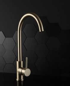 a kitchen faucet that is on a black counter with hexagonal tiles