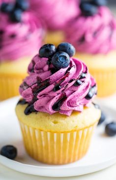 blueberry cupcakes with purple frosting and blueberries on top are shown