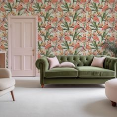 a green couch sitting in front of a pink door and wall with flowers on it