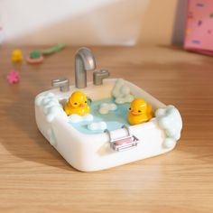 two rubber ducks sitting in a bathtub with soap bubbles on the floor next to it